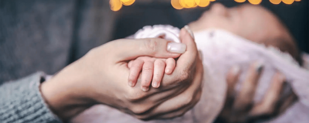 A woman holding her baby's hand